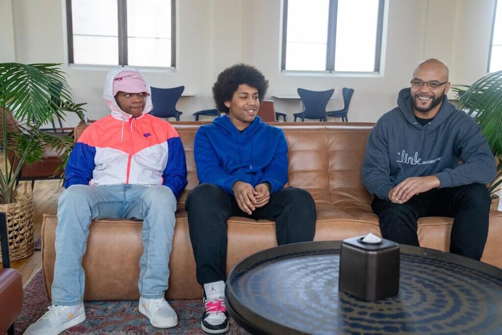 Two male youth speaking with a male adult