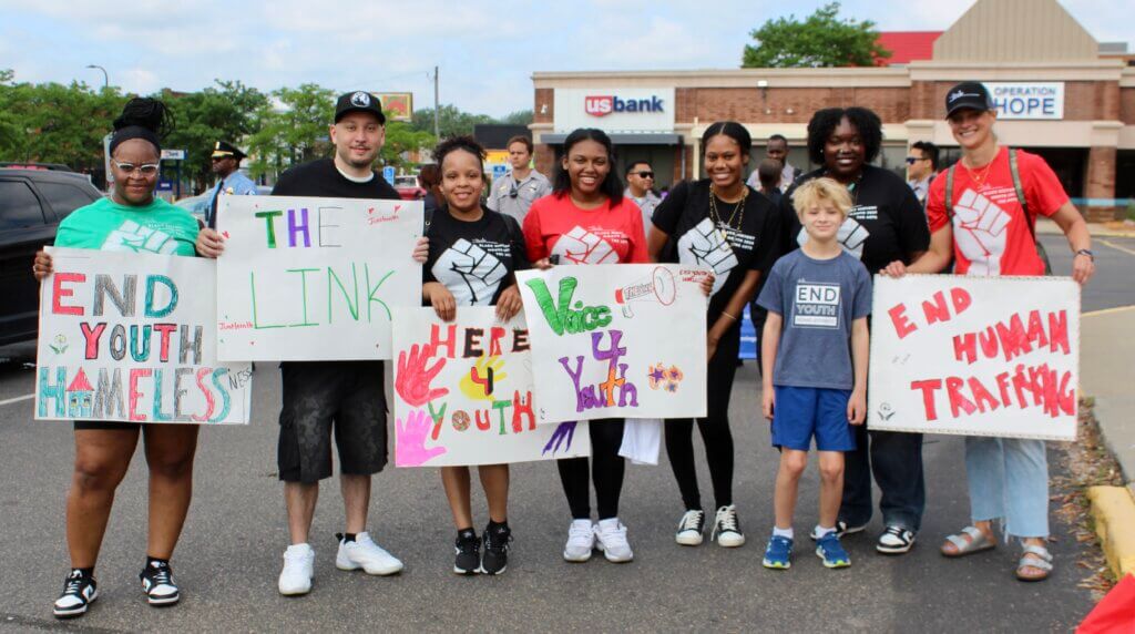 Youth and adults holding "end youth homelessness" signs in a Juneteenth Parade