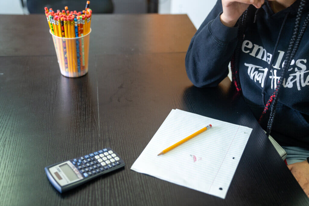 Youth hands on table with pencils, notebook and calculator
