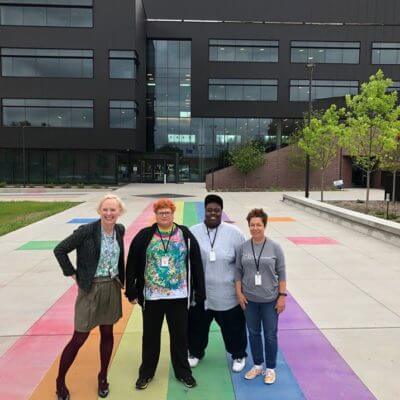 Four people standing on a rainbow sidewalk