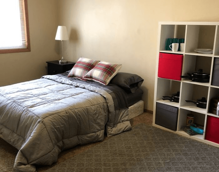 Youth bedroom with a queen bed that has a grey bedspread 