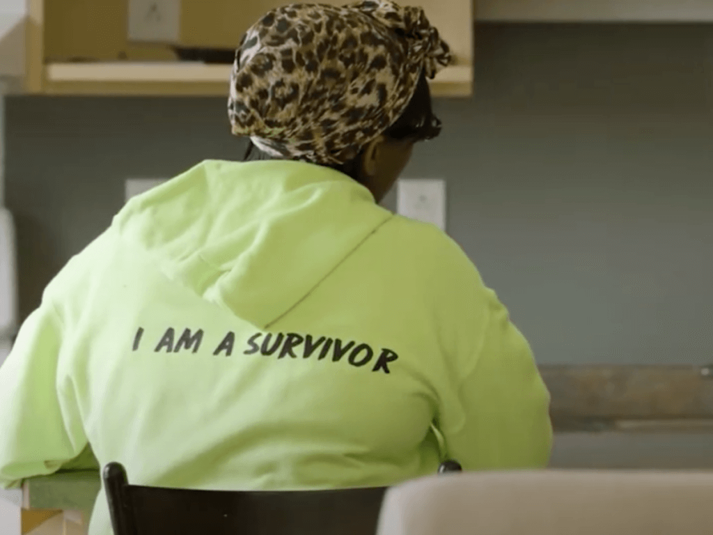 Youth wearing a sweatshirt that reads "I am a survivor" on the back